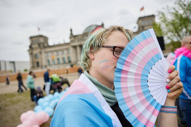 A person stands in front of Germany’s Bundestag with a fan in the transgender colours during a protest against the Self-Determination Act by women’s groups. Photo: dpa