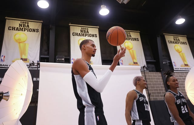 Spurs’ Victor Wembanyama (center) twirls the ball as he along with Devin Vassell (from right) and Jeremy Sochan get ready to pose for photos during Spurs Media Day on Monday, Oct. 2, 2023.