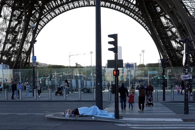 A homeless person sleeps just next to the Eiffel Tower. With the Paris Games 100 days away, French police carried out a large-scale eviction at an abandoned factory, located on the southern outskirts of Paris, on Wednesday. Photo: AP