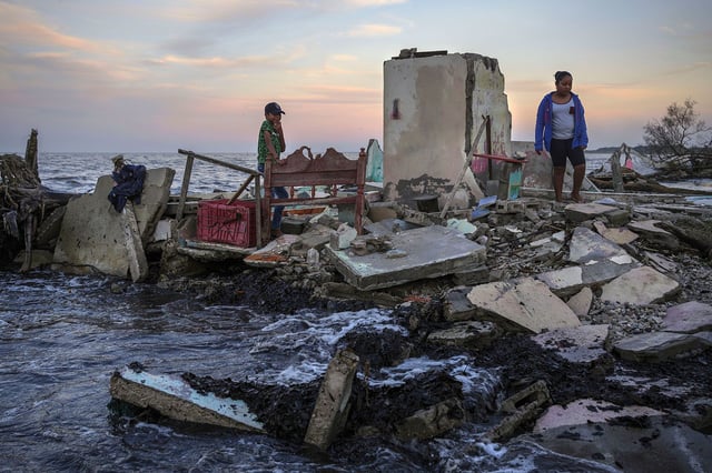 FILE - Yahir Mayoral and Emily Camacho walk amid the rubble of their grandmother's home, destroyed by flooding driven by a sea-level rise in their coastal community of El Bosque, in the state of Tabasco, Mexico, Nov. 30, 2023. DrivenÂ by climate change, sea-level rise and increasingly ferocious storms are eroding thousands of miles of Mexico's coastline facing both the Gulf and theÂ Pacific Ocean. (AP Photo/Felix Marquez, File)