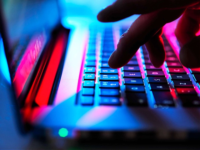 Man typing at his laptop computer at night - stock photo