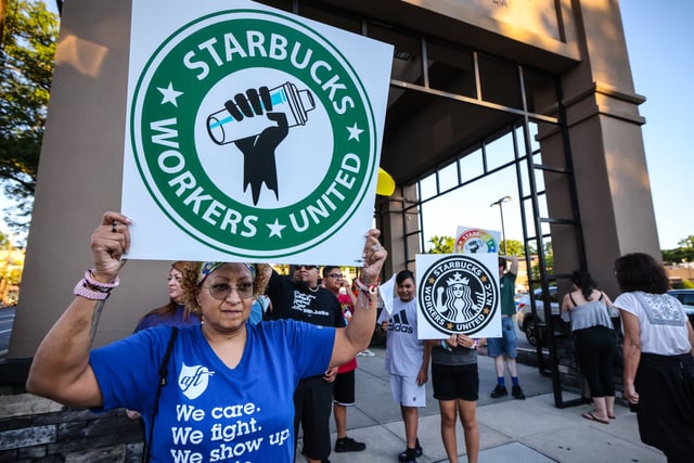 A woman holds up a sign as she joins other protestors in a rally against what they perceive to be union busting tactics, outside a Starbucks in Great Neck, New York, demanding the reinstatement of a former employee on August 15, 2022.