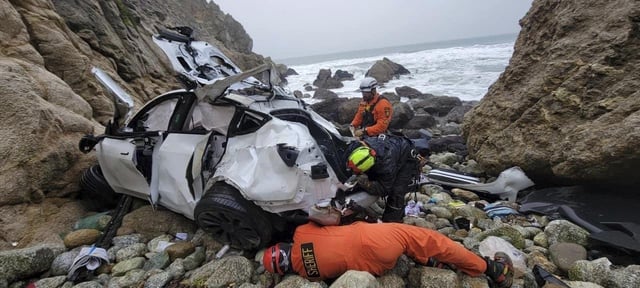 In this photo provided by the San Mateo County Sheriff's Office, emergency personnel respond to the Tesla that Dharmesh Patel is accused of driving over a cliff, his wife and two children in the car, in January 2023.