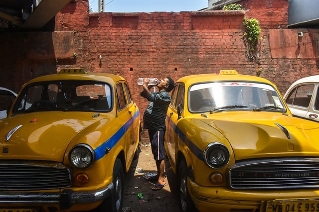 A taxi driver is drinking water at the taxi stand during the heat wave in Kolkata, India, on April 21, 2024.