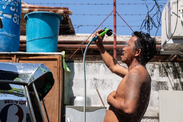 A man showers with a hose during hot weather in Manila on Sunday. The Philippines will suspend in-person classes in all public schools for two days due to extreme heat. Photo: AFP