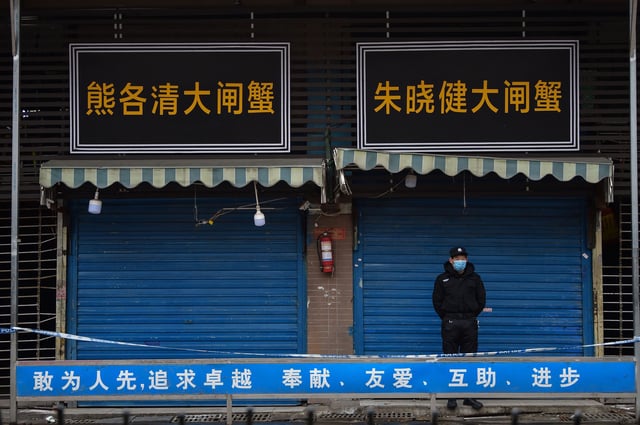 A security guard stands outside a wet market in Wuhan linked to some of the earliest known cases of Covid-19.