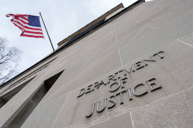 WASHINGTON, DC - JANUARY 30: The US Flag flies above a sign marking the US Department of Justice (DOJ) headquarters building on January 20, 2024, in Washington, DC. (Photo by J. David Ake/Getty Images)