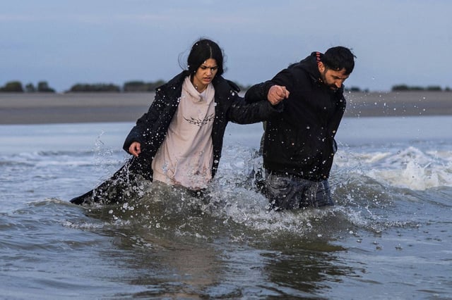 Migrants walk in the water trying to board a smuggler’s boat in an attempt to cross the English Channel. Photo: AFP
