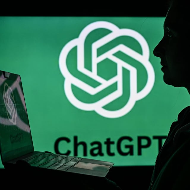 a person with a notebook computer silhouetted against the OpenAI logo