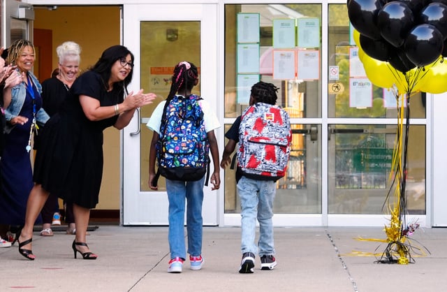 First grade teacher, Dolores Smith, greets students on the first day of school at Ethel M. Taylor Academy, Thursday, August 17, 2023. The pre-k through 6th grade in Millville, has an enrollment of 247 students. Principal Pia Headen said teachers and other supporters line the walkway and clap as students enter the building. The Cincinnati Public School is considered a neighborhood school and many of the students walk to school.