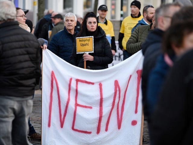 24 March 2023, Mecklenburg-Western Pomerania, Grevesmühlen: People protest with signs and flags at a demonstration against the refugee accommodation in the village of Upahl on the market square. The rally was held under the slogan "Upahl continues to say NO!". Photo: Frank Hormann/dpa (Photo by Frank Hormann/picture alliance via Getty Images)