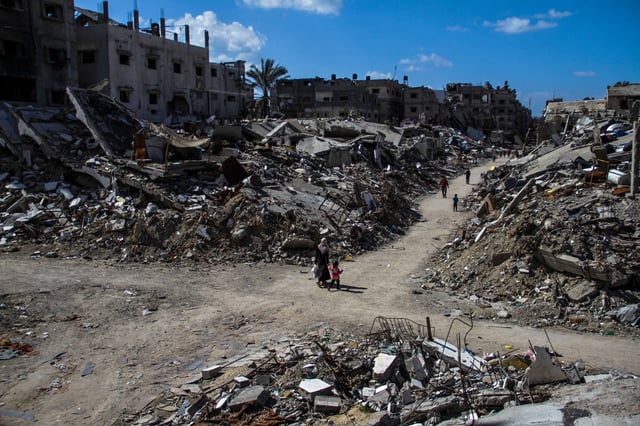 People walk past the ruins of buildings destroyed by Israeli bombardment in Jabalia refugee camp in Gaza on March 22, 2024.