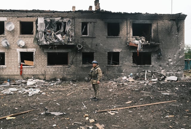 A Ukrainian police officer inspects a damaged building during the evacuation of local people from territories bordering Russia, in the city of Vovchansk, Kharkiv region. Photo: EPA-EFE