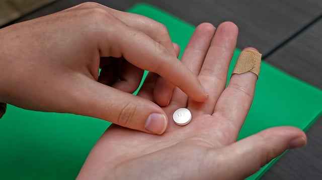 A patient prepares to take the first of two combination pills, mifepristone, for a medication abortion during a visit to a clinic in Kansas City, on October 12, 2022.