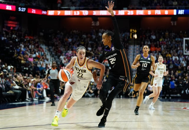 Indiana Fever guard Caitlin Clark drives the ball against Connecticut Sun forward DeWanna Bonner in her WNBA debut.