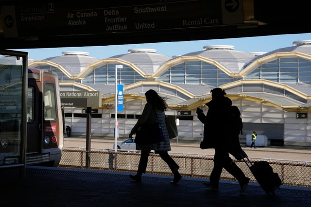 Travelers run to a waiting Metro train across from a terminal at Ronald Reagan Washington National Airport in Arlington, Virginia, in November 2022.