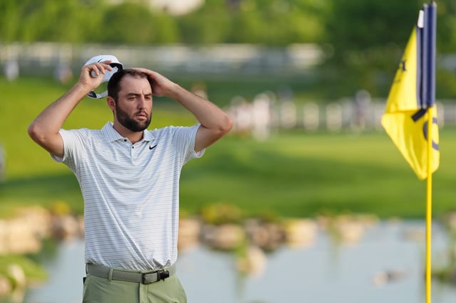 Scottie Scheffler takes off his hat while lining up a shot on the 18th green during the first round.