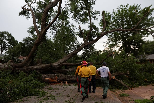 Houston Fire Department Wildland District 14 crews cut and remove pieces of a downed tree blocking a street after a severe storm caused widespread damage in Spring Branch, Texas, on May 17, 2024.