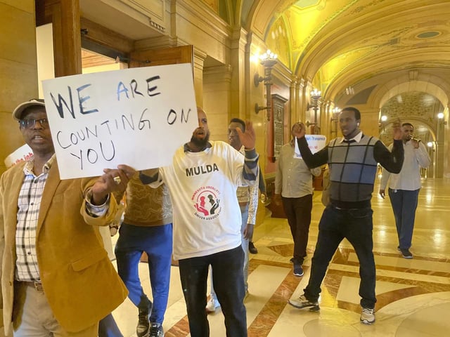 Supporters of Minnesota legislation -- which would require ride-hailing companies to increase pay for drivers -- walk through the State Capitol building, holding signs that say "WE ARE COUNTING ON YOU" and shirts that say "MULDA Minnesota Uber/Lyft Driver Association," in St. Paul, Minn.,, May 17, 2024. Uber and Lyft have said they will leave the state if Minnesota lawmakers pass legislation that requires the companies to raise driver pay by more than they want to.