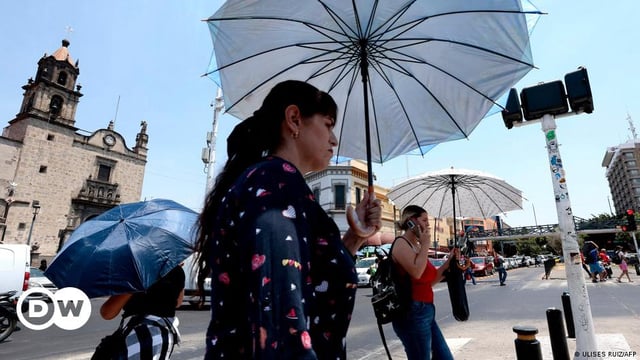 People protect themselves from the sun with an umbrella as they walk during a heat wave hitting the country in Guadalajara, Jalisco State, Mexico