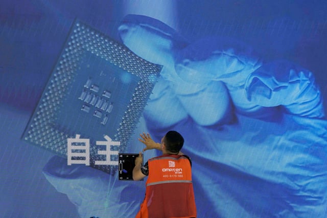 A worker checks a display panel showing a semiconductor and the Chinese characters for “Independence” during the World Artificial Intelligence Conference in Shanghai on July 5, 2023. Photo: AP