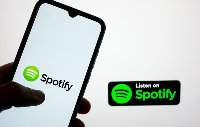 Spotify logo displayed on a smartphone screen and desktop monitor. CREDIT: Nikolas Kokovlis/NurPhoto via Getty Images