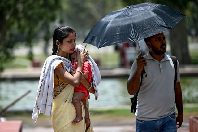 A woman shields her child from the sun during severe heatwave on a hot summer day in New Delhi on May 29, 2024. Temperatures in India's capital have soared to a record-high 49.9 degrees Celsius (121.8 Fahrenheit) as authorities warn of water shortages in the sprawling mega-city. (Photo by Money SHARMA / AFP) (Photo by MONEY SHARMA/AFP via Getty Images)