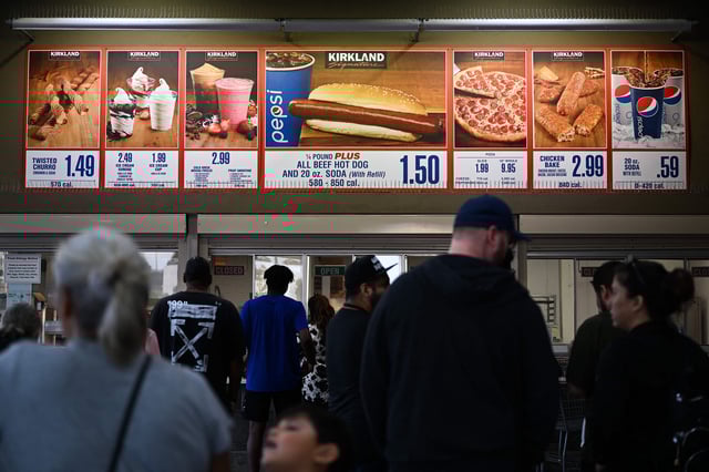Customers wait in line to order below signage for the Costco Kirkland Signature $1.50 hot dog and soda combo, which has maintained the same price since 1985 despite consumer price increases and inflation, at the food court outside a Costco Wholesale Corp. store on June 14, 2022 in Hawthorne, California.