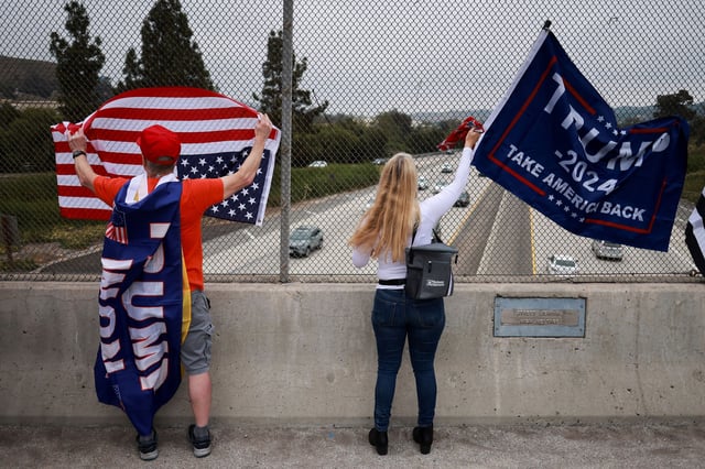 People stand with flags as "805 Patriots" take part in a rally in support of former U.S. President Donald Trump during what they call a "MAGA Cruise to stand up for Trump", in Thousand Oaks, California, U.S. June 1, 2024.