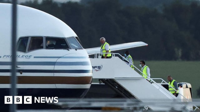 Members of staff board a plane first earmarked to transport migrants to Rwanda, at Boscombe Down airbase in Wiltshire.