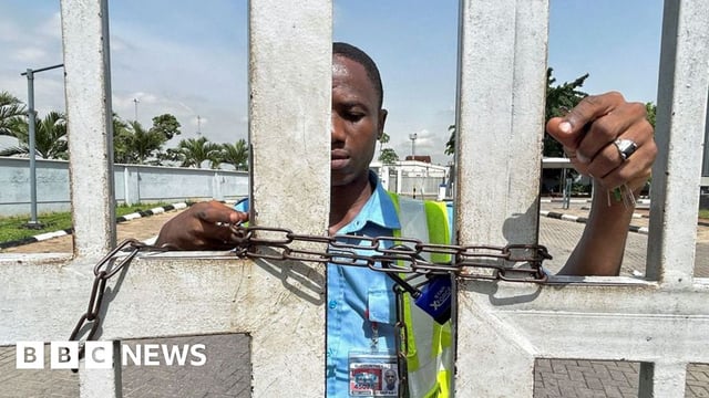 A worker stands by the gate of the domestic airport, which has been chained to prevent passengers from entering the premises, as Nigeria's main labour unions called for an indefinite strike from Monday after failing to agree to a new minimum wage with the government, in Lagos, Nigeria, 3 June 2024