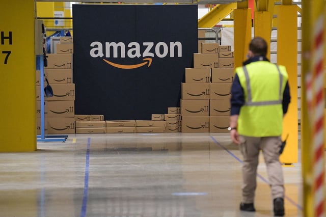 An US giant Amazon employee passes by its logo on the opening day of the new distribution center in Augny, eastern France, on September 23, 2021.