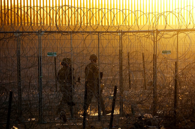 Members of the Texas National Guard stand guard near a razor wire fence to inhibit the crossing of migrants into the United States, seen from Ciudad Juarez, Mexico, June 4, 2024. REUTERS/Jose Luis Gonzalez