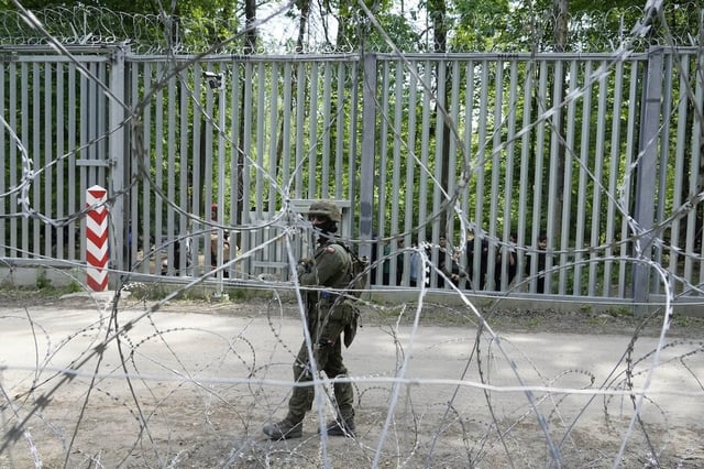 A Polish soldier guards the metal barrier bordering Belarus near Bialowieza Forest on May 29, 2024. Poland claims that Belarus and Russia are behind a surge in refugees heading to Europe.