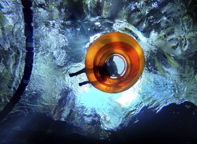Sunlight filters through a colorful tube as a swimmer chills out in the 72-degree Fahrenheit water at the top of Rock Springs Run at Kelly Park, Thursday, June 6, 2024, in Apopka, Fla. Central Floridians will be seeking more relief from the heat as temperatures are forecast to be near record-breaking —with highs in the upper 90s— through the weekend. (Joe Burbank/Orlando Sentinel via AP)