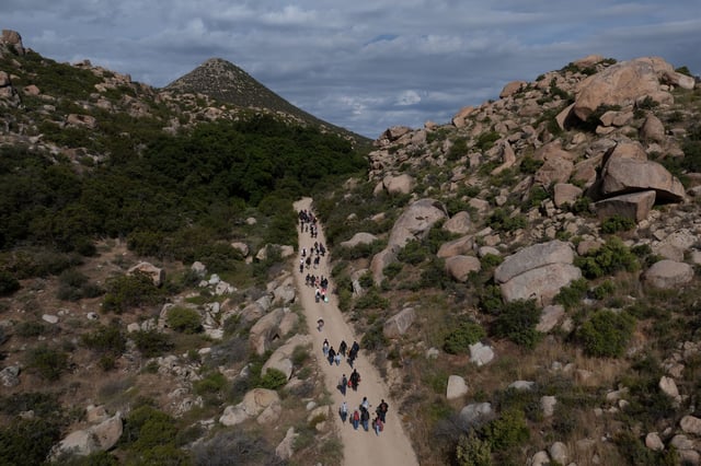 A drone view shows asylum seeking migrants from China and Turkey as they climb a hill while looking to surrender to immigration officials after crossing the border into the United States from Mexico in Jacumba Hot Springs, California, U.S., May 20, 2024.