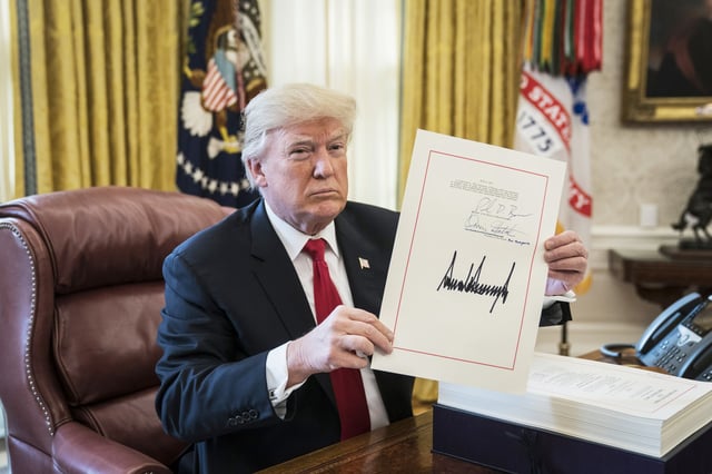 President Donald Trump signs the Tax Cut and Reform Bill, a $1.5 trillion tax overhaul package, into law in the Oval Office in 2017. 