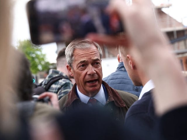 A member of the public takes a photograph on a phone of, Leader of Reform UK Nigel Farage (C) as he speaks with members of the public during a visit to Ashfield in north England, on June 11, 2024, ahead of the UK general election of July 4. (Photo by Darren Staples / AFP) (Photo by DARREN STAPLES/AFP via Getty Images)