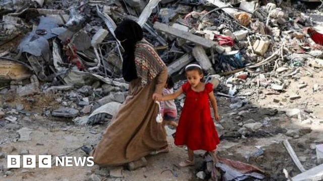 A woman and child walk among debris in Nuseirat refugee camp in the central Gaza Strip, June 9, 2024.