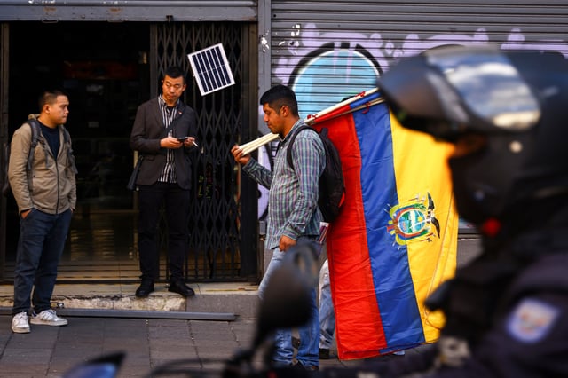 A person walks as he holds Ecuadorian flags in Quito, Ecuador, on June 12, 2024.