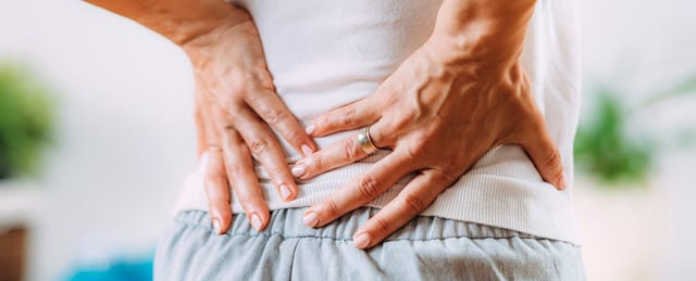 person holding hands on lower back