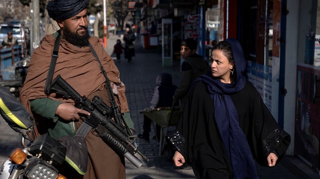 A woman looks at a Taliban fighter on the street in Kabul, Afghanistan, Dec. 26, 2022 (AP photo by Ebrahim Noroozi).