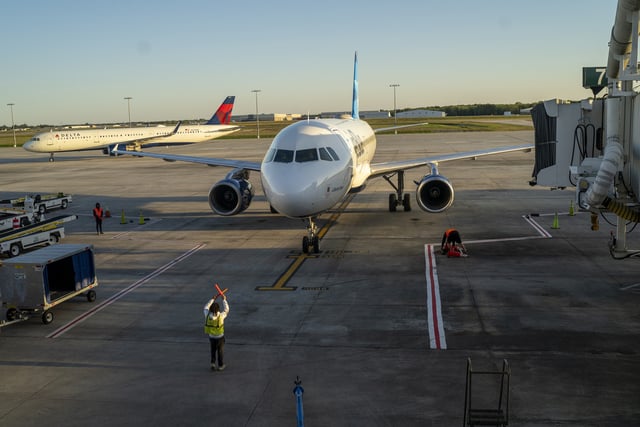 Pictured above, a ground crew employee guides an arriving plane to airbridge position March 26, 2022 at the Savannah/Hilton Head International Airport in Savannah, Georgia.