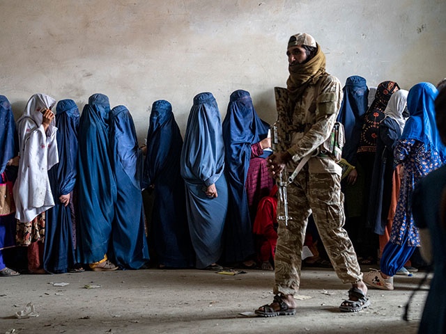 A Taliban fighter stands guard as women wait to receive food rations distributed by a humanitarian aid group, in Kabul, Afghanistan, on May 23, 2023. Human Rights Watch said Monday, Feb. 12, 2024 that Afghanistan’s public health system has been hit hard following a sharp reduction in foreign assistance, coupled with serious Taliban abuses against women and girls, jeopardizing the right to healthcare of millions of Afghans. (AP Photo/Ebrahim Noroozi, File)
