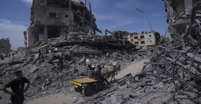 Palestinians walk through the destruction in the wake of an Israeli air and ground offensive in Khan Younis, southern Gaza Strip, Monday, April 8, 2024. Israel says it has withdrawn its last ground troops from the city, ending a four-month operation. (AP Photo/Fatima Shbair)
