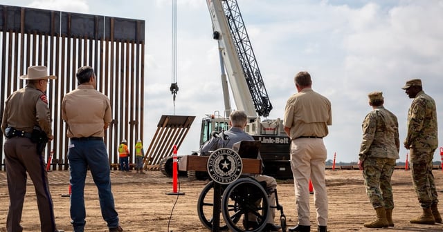 Gov. Greg Abbott looks at crane lifting a section of the border wall in place after giving a press conference at Rio Grande City on Dec. 18, 2021.