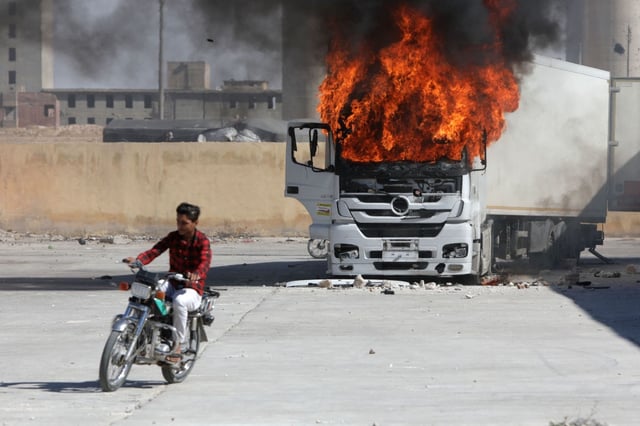 A man rides a motorcycle near a burning truck during protests against Turkey in al-Bab, in the northern Syrian opposition held region of Aleppo, on July 1, 2024.