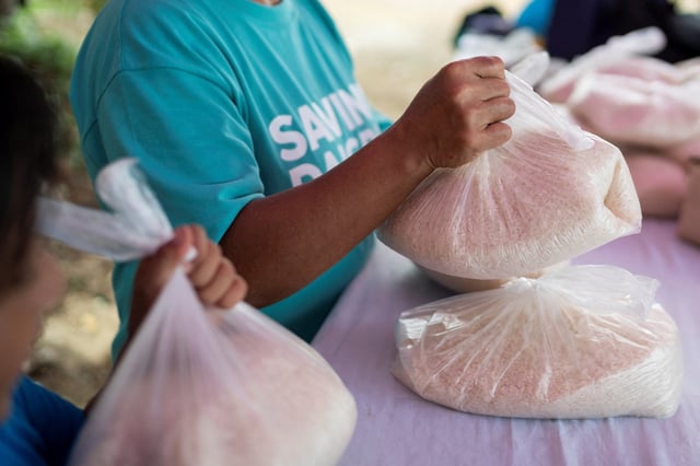 A woman receives a plastic bag of rice in exchange for picking up plastic waste in the Philippines. Photo: Reuters