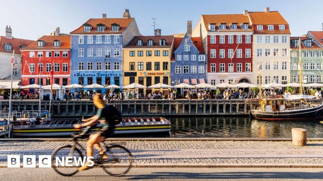 A cyclist passes a row of colourful houses