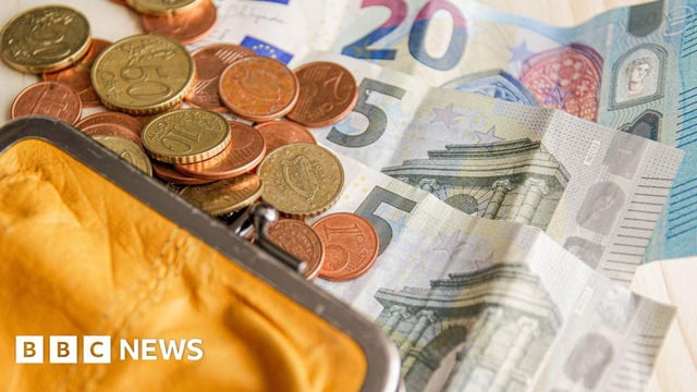 Orange coin purse with multiple euro coins spilling across Euro banknotes